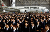 Недавно принятые на работу сотрудники Japan Airlines присутствуют на церемонии вступления в должность в ангаре международного аэропорта «Ханэда» в Токио.