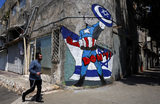Мужчина проходит мимо граффити, на которм изображен президент США Джо Байден в образе супергероя Капитана Америки. Тель-Авив, Израиль.