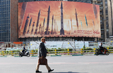 Мужчина идет на фоне рекламного щита с изображением иранских ракет на улице в Тегеране, Иран.
