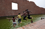 Дети прыгают в водоем Мемориала интеллектуалов- мучеников в Райербазаре, чтобы охладиться во время жары в Дакке, Бангладеш.