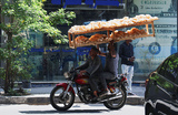 Египетские уличные торговцы с хлебом проезжают мимо пункта обмена валюты в Каире, Египет.