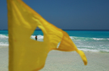 Желтый флаг «Осторожно» установлен на пляже из-за прихода урагана «Берил» в городе Канкун, Мексика.
