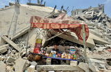 Уличный торговец сидит среди обломков зданий на юге сектора Газа.