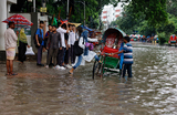 Девочка садится в рикшу на улице, затопленной из-за сильного дождя, в Дакке, Бангладеш.