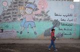 Палестинский ребенок проходит мимо рисунка на стене, предупреждающего об опасности неразорвавшихся боеприпасов. Дейр-эль-Балах, центр сектора Газа.