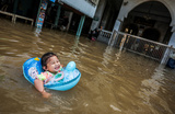 Девочка плавает на улице, затопленной в результате сброса воды с плотины на реке Чао Прайя. Пригород Бангкока, Тайланд.