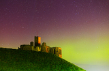 Северное сияние над древним замком Уоркуорт в Нортумберленде, Великобритания.